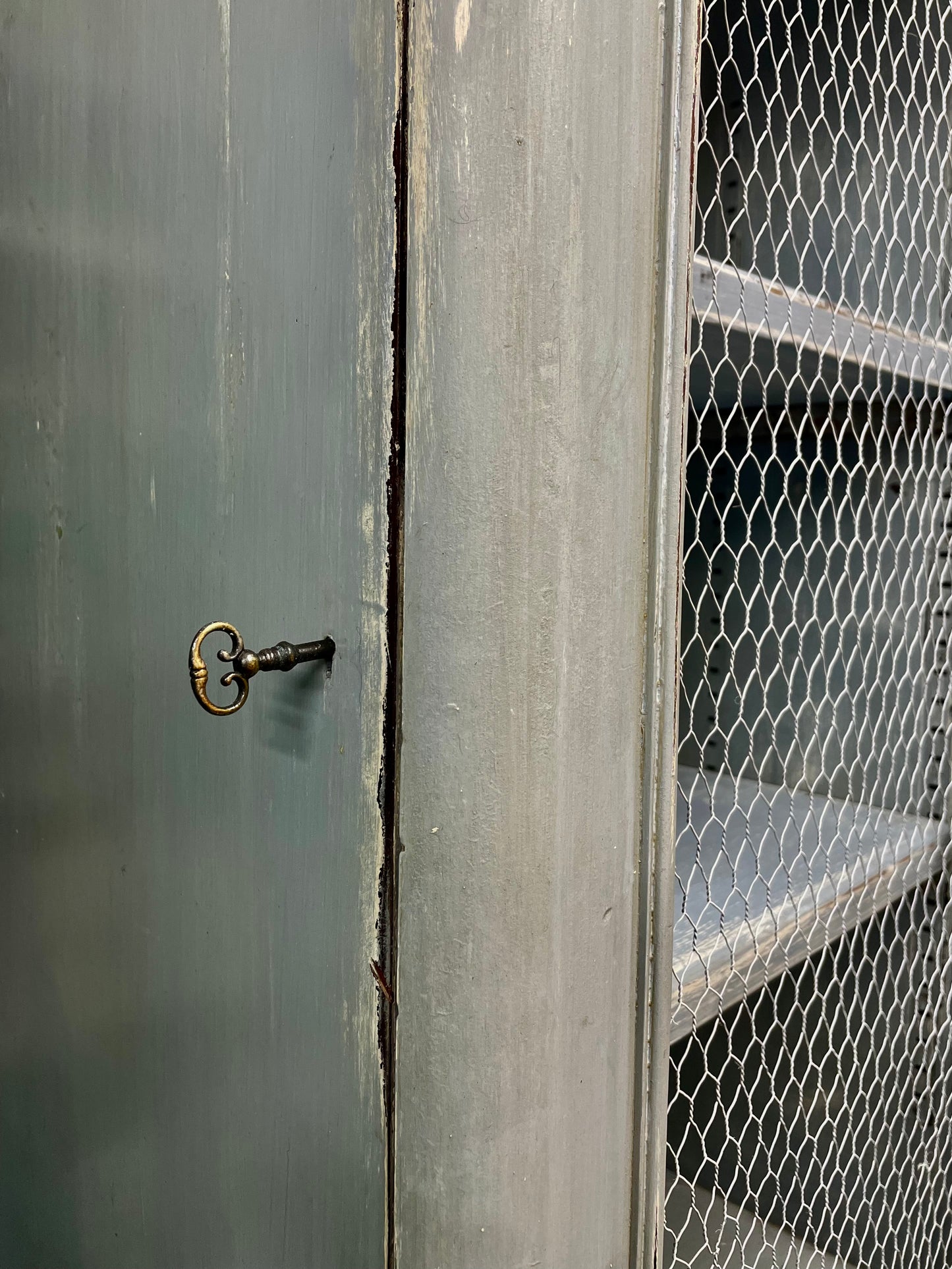 Vintage chicken wire cabinet painted in layers of traditional milk paint