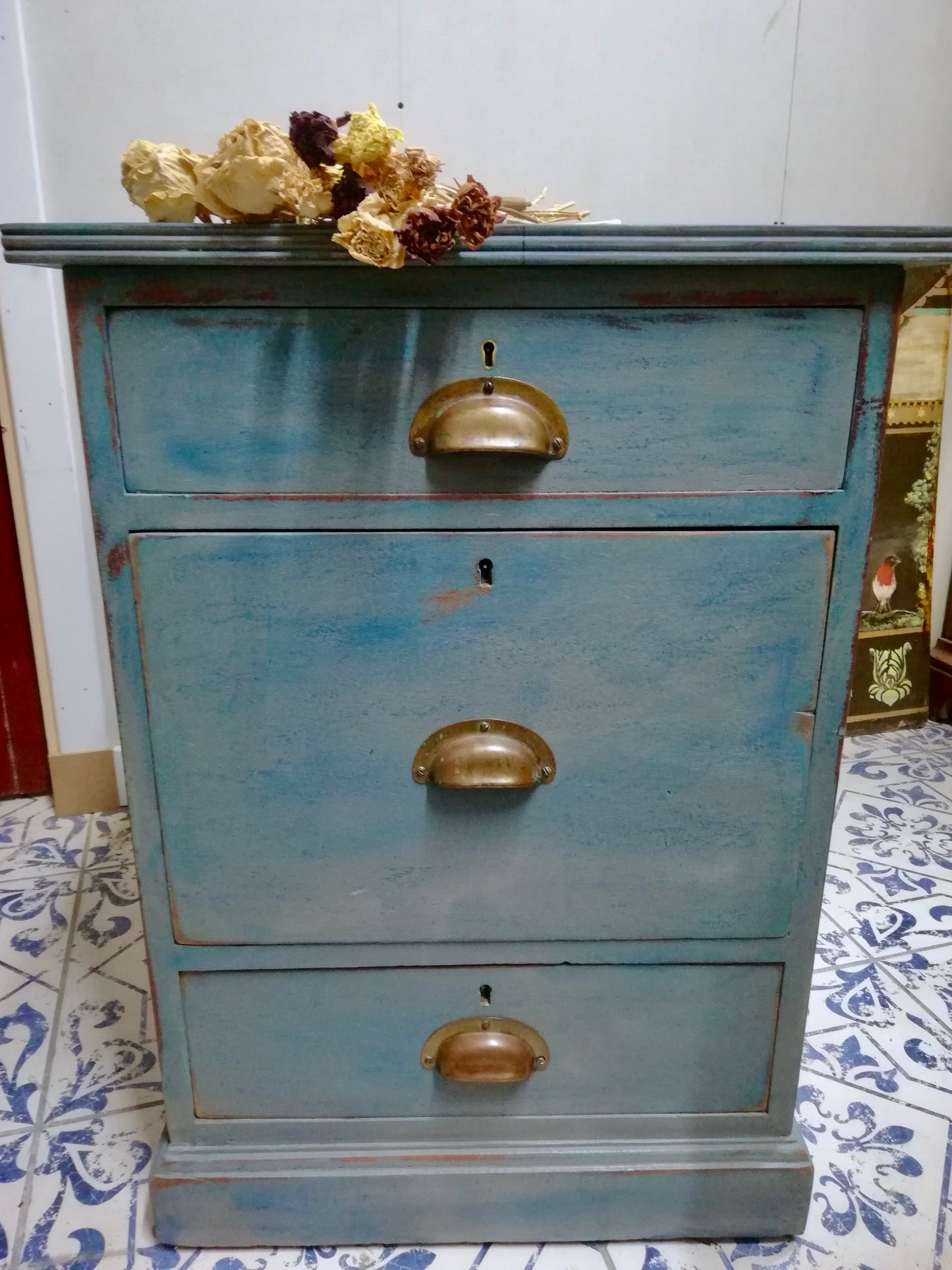 Vintage wooden filing cabinet painted in chippy layers of blue and grey.