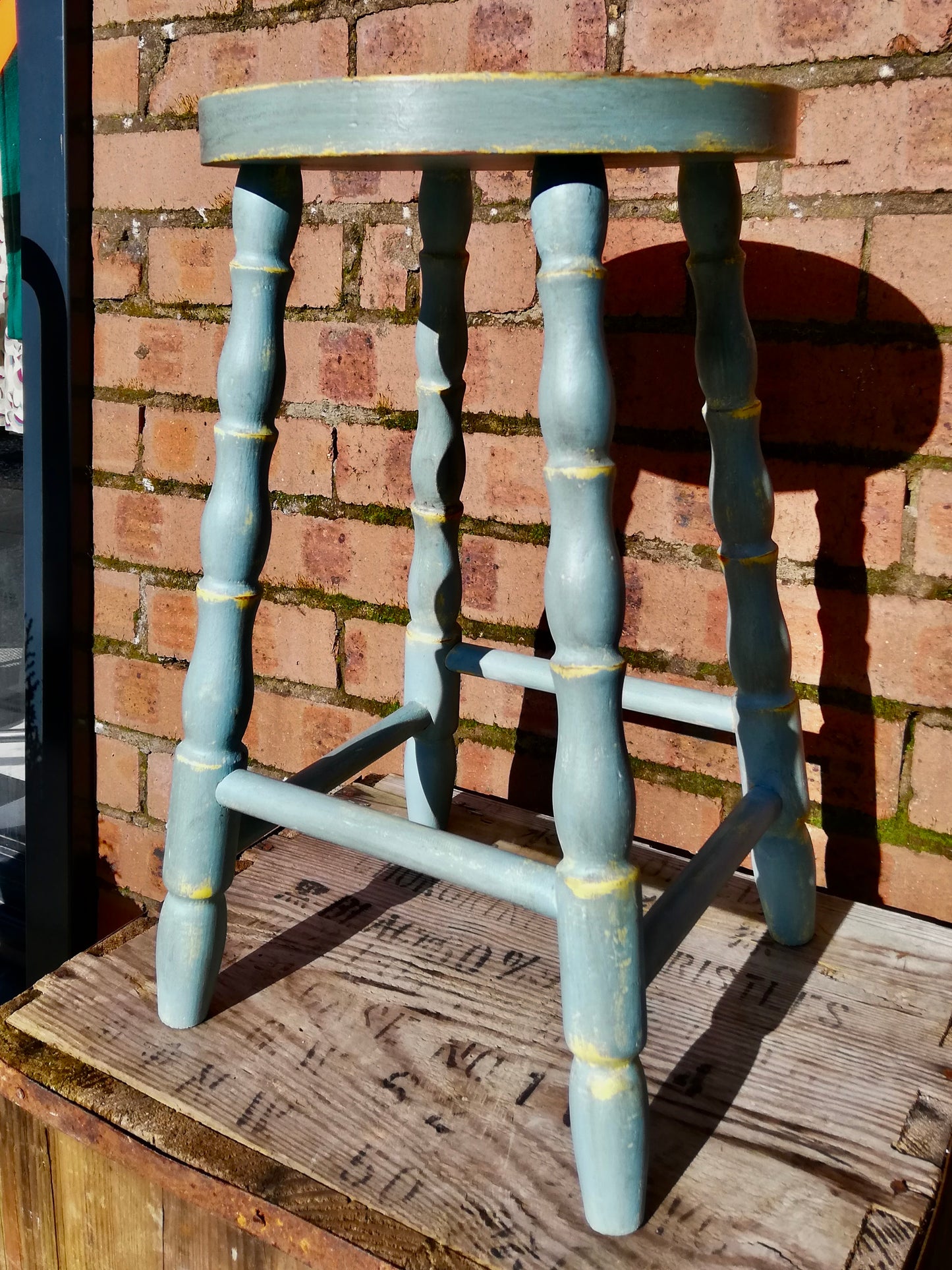 Vintage wooden stool painted in layers of chippy yellow and blue paint