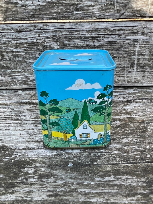 Vintage 1980s tin children's money box decorated with a countryside village scene