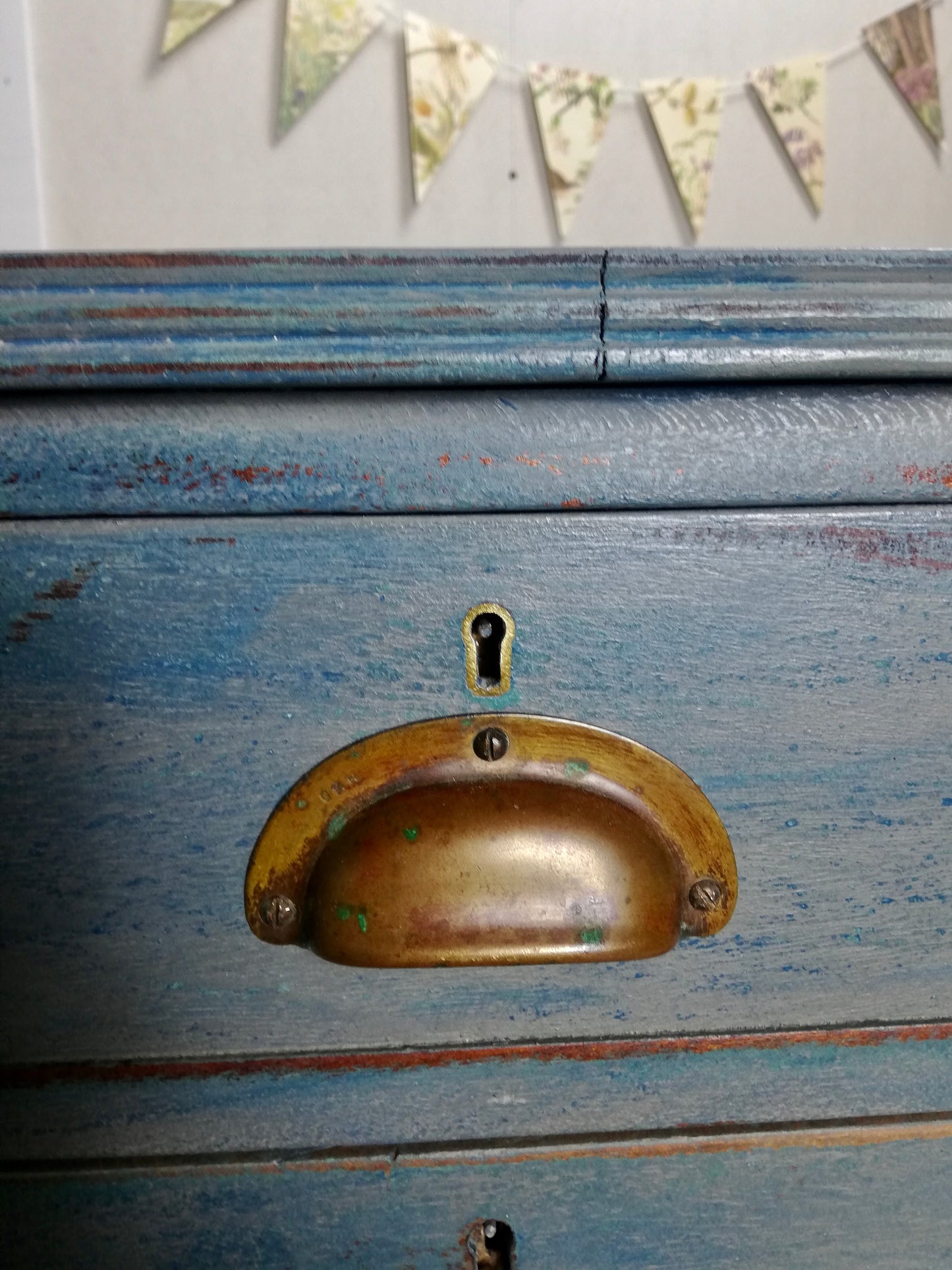 Vintage wooden filing cabinet painted in chippy layers of blue and grey.