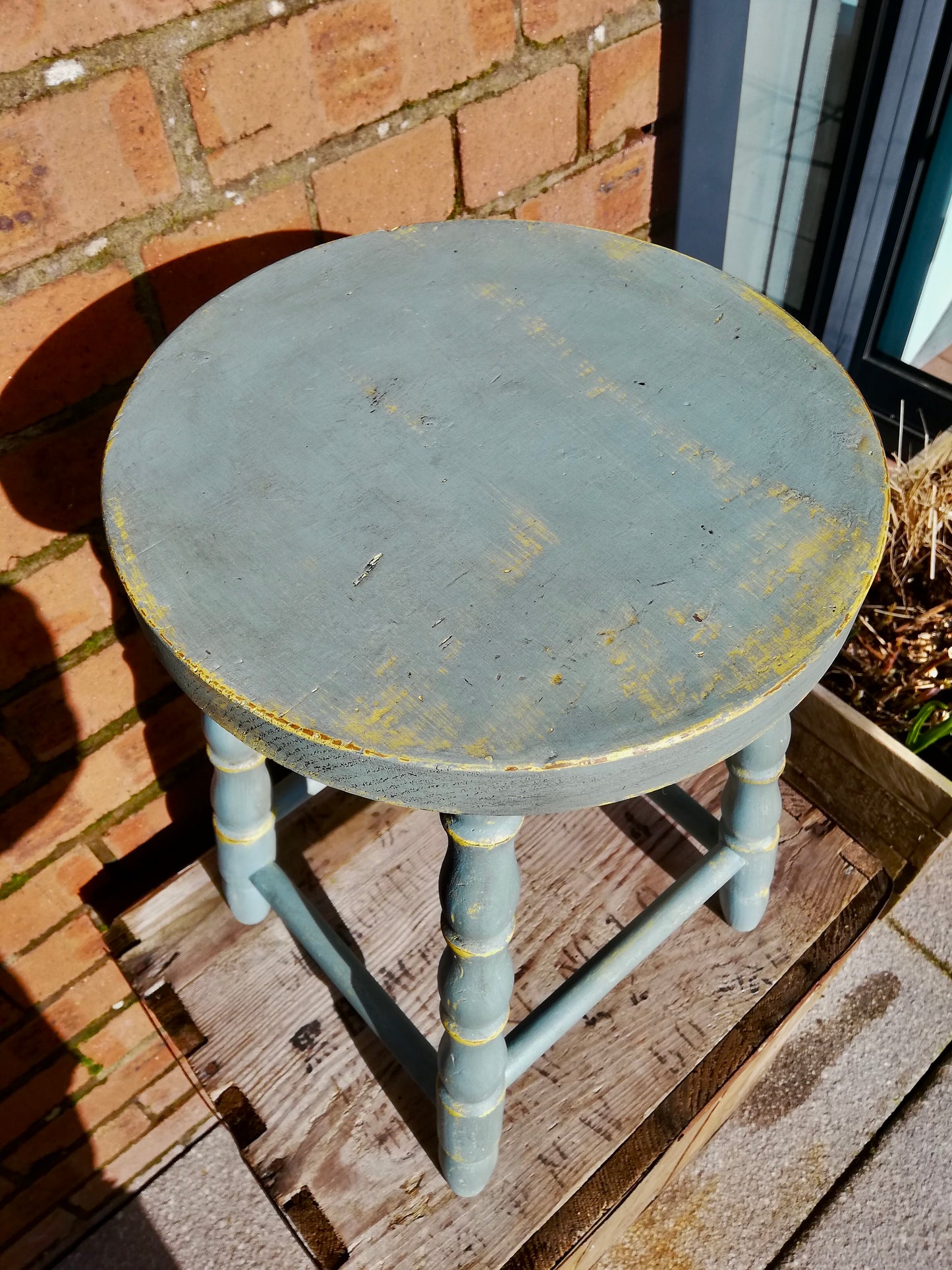 Vintage wooden stool painted in layers of chippy yellow and blue paint