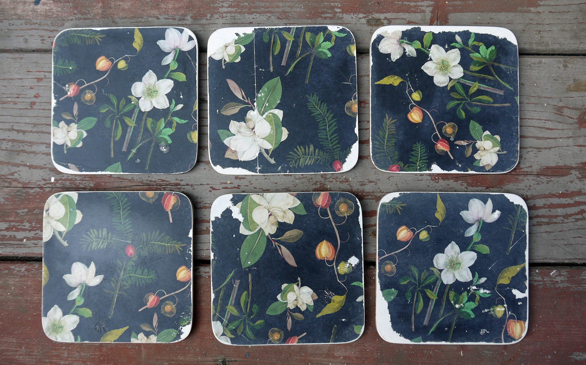 Set of six vintage paper coasters in dark grey and floral design on white.